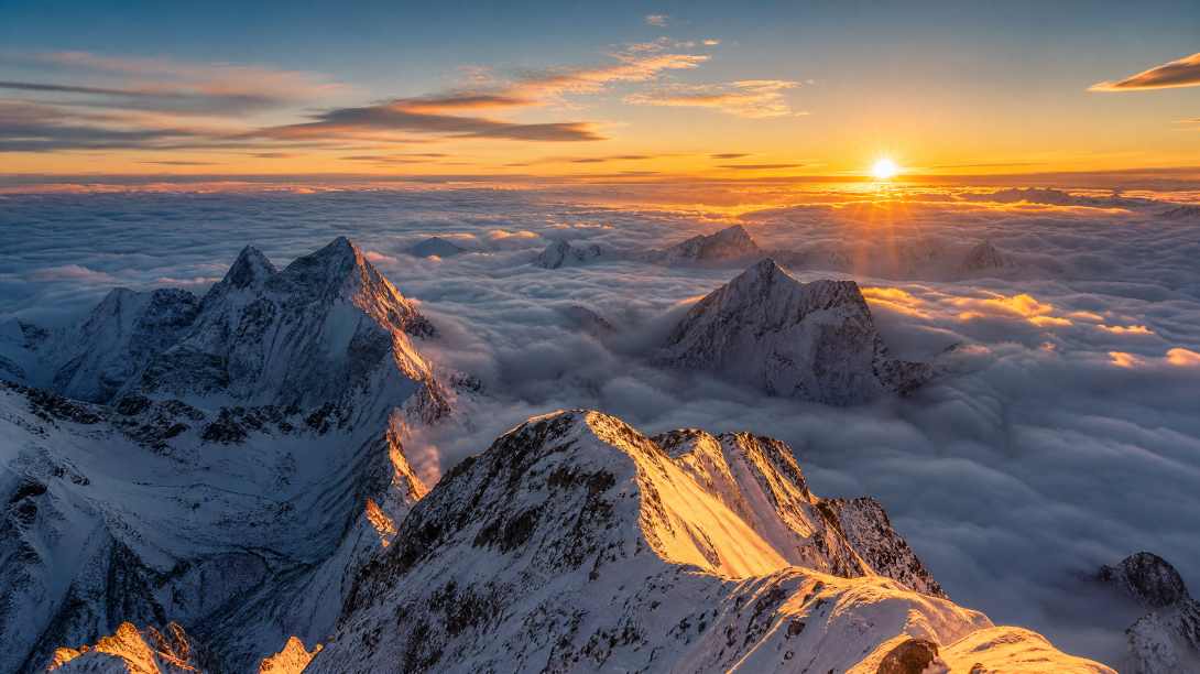 雪山之巅，云海翻涌，日出时分，金色阳光照在雪峰，壮观，广角 - 唯爱壁纸